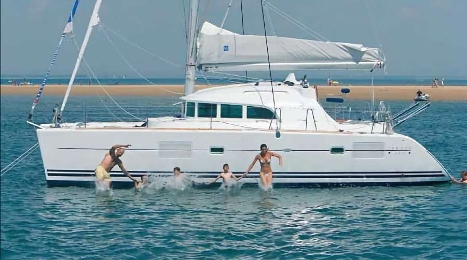 Grupo saltando al agua desde un catamarán Lagoon 38 en renta frente a una playa de la Bahía de Banderas a la que sólo se llega en barco